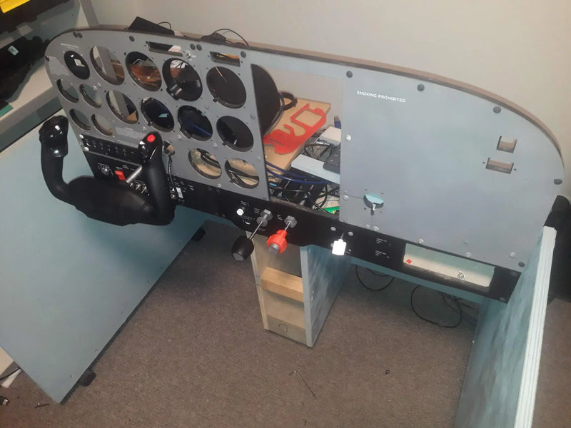 Pilot's cockpit simulator with controls and instruments on a stand.