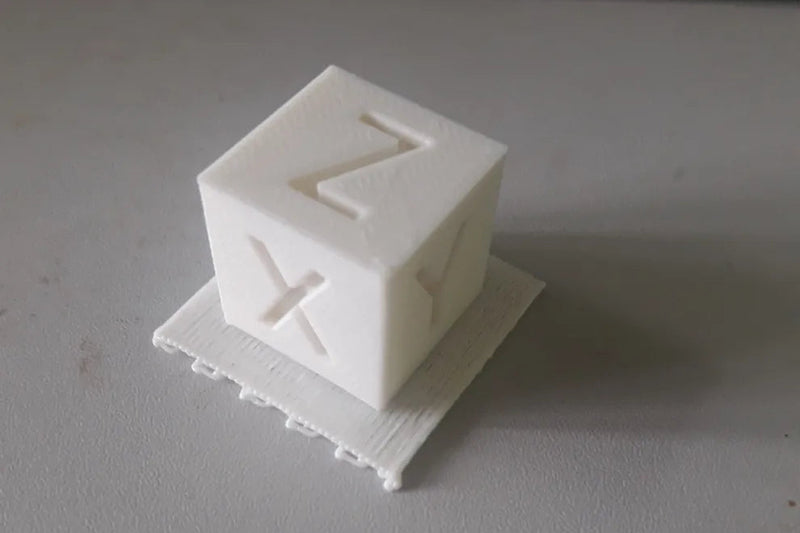 White 3D-printed cube with 'XYZ' on a gray surface