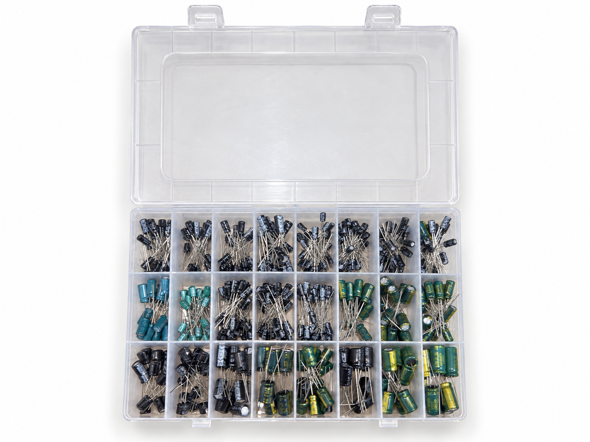 Top view of the open capacitor kit showing 24 compartments in 3 rows of 8, small black capacitors at the back and larger green and black ones at the front
