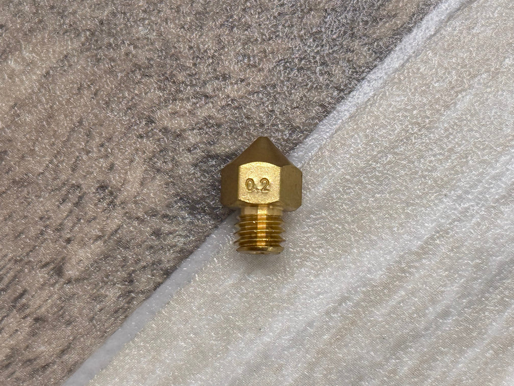 Brass 3D printer nozzle on a textured surface