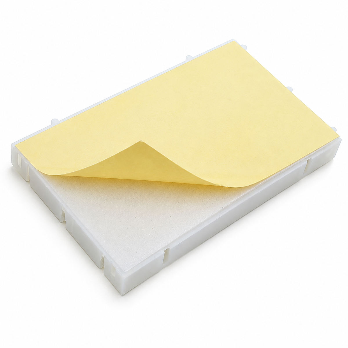 Underside of the 400 point breadboard with the yellow backing paper peeled back to show the self-adhesive pad